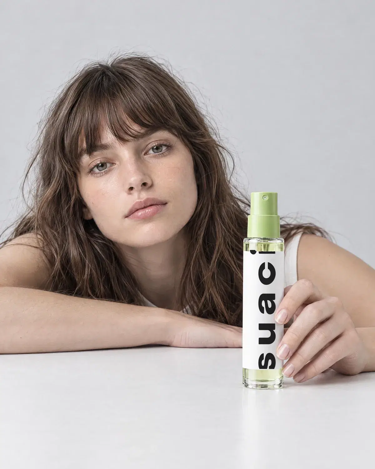 a woman resting her arms on a table holding a suaci mist bottle